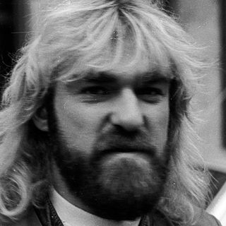 Long-haired man in urban setting, mid-1970s style.