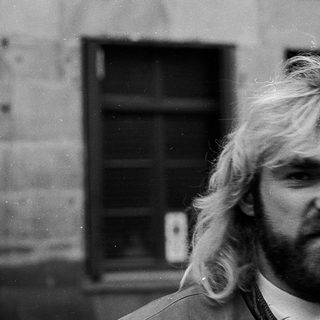 Long-haired man in urban setting, mid-1970s style.