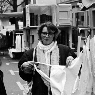 Two women examining clothing at an outdoor market stall.