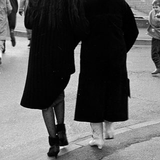 People walking on wet pavement near a curb.
