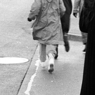 People walking on wet pavement near a curb.
