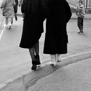 People walking on wet pavement near a curb.