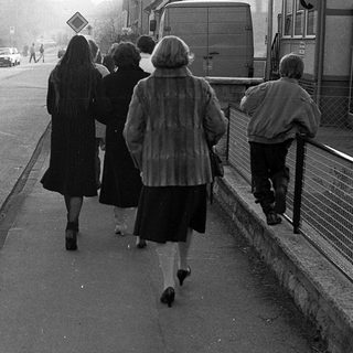 People walking together on a sidewalk near a road.