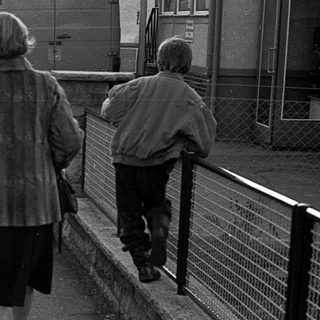 People walking together on a sidewalk near a road.
