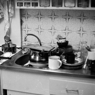 Vintage kitchen with stove, sink, and dishes.