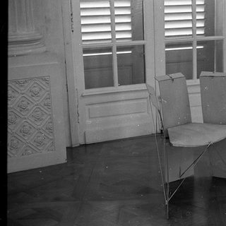 Empty room with folding chair, ornate chair, open shuttered window.