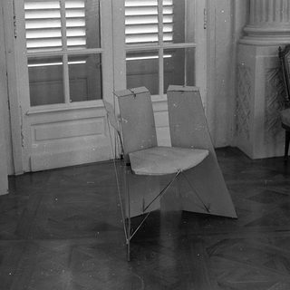 Empty room with folding chair, ornate chair, open shuttered window.