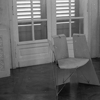 Empty room with folding chair, ornate chair, open shuttered window.