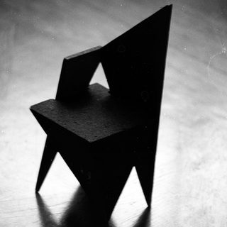 Abstract geometric chair sculpture in dark material.