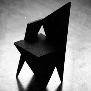 Minimalist geometric black chair silhouette.