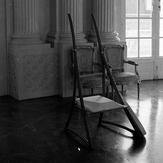 Elegant room with classical columns, vintage chairs, ladder.