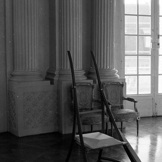 Elegant room with classical columns, vintage chairs, ladder.