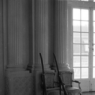 Elegant room with classical columns, vintage chairs, ladder.