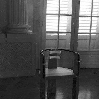 Empty room with modern chair, classical column, wet floor.