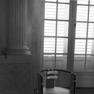 Empty room with modern chair, classical column, wet floor.