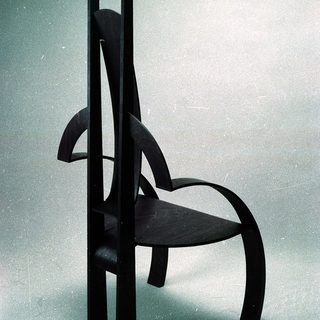 Modernist black wooden chair with sculptural, curved design.