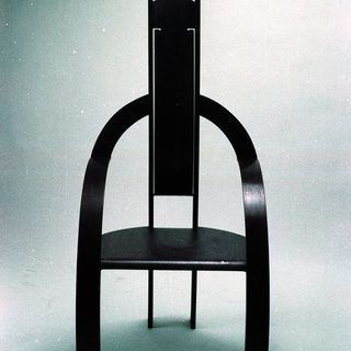 Modern black wooden chair with curved legs.