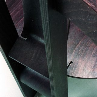Modern geometric wooden chair with curved backrest.