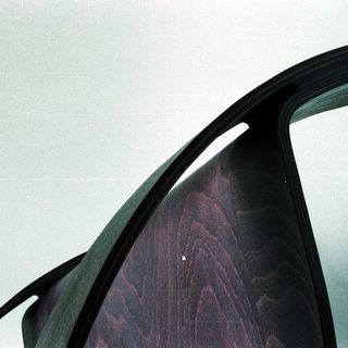 Curved wooden chair seat with black metal frame.