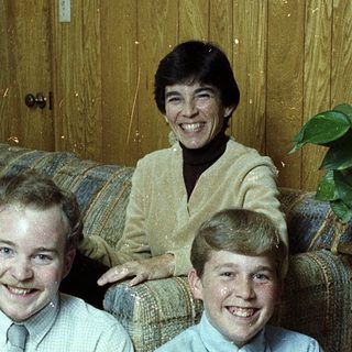 Family portrait with three smiling individuals indoors.