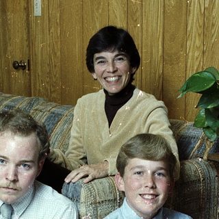 Family portrait with three members indoors.