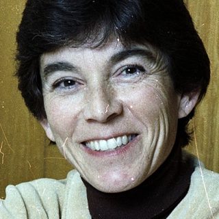 Smiling woman in light-colored sweater indoors.
