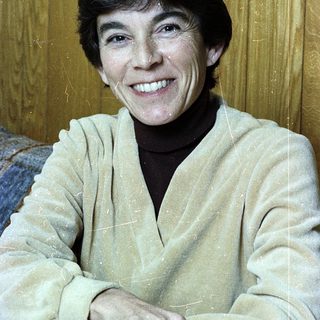 Smiling woman in light-colored sweater indoors.