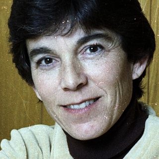 Woman smiling indoors in casual sweater.
