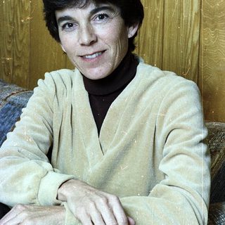Woman smiling indoors in casual sweater.