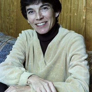 Woman smiling indoors wearing light-colored sweater.