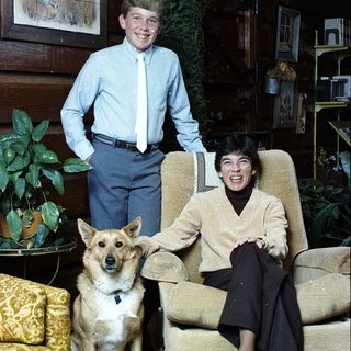 Family portrait with man, boy, and dog indoors.