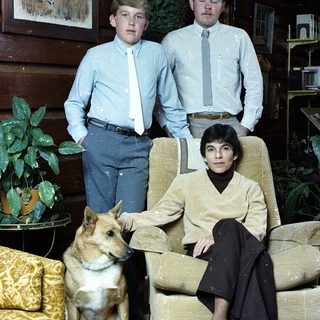 Family portrait with two boys, woman, and dog indoors.