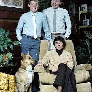 Family portrait with two young men and woman, dog, indoors.
