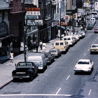 Urban street scene with mid-century traffic and buildings.