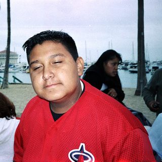 Man wearing red baseball jersey near waterfront.