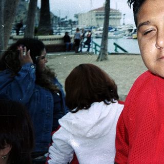Man wearing red baseball jersey near waterfront.