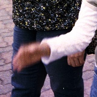 Mother and child walking together outdoors in a shopping area.