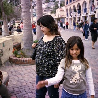 Mother and child walking together outdoors in a shopping area.
