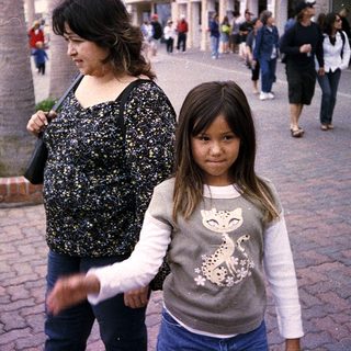 Mother and child walking together outdoors in a shopping area.