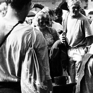 People gathering around a large communal food pot outdoors.