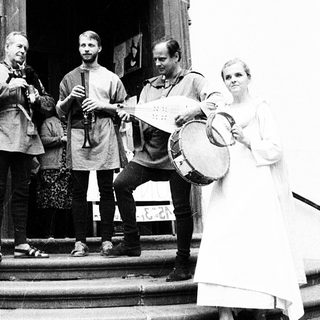 Group performing traditional music outside church entrance.