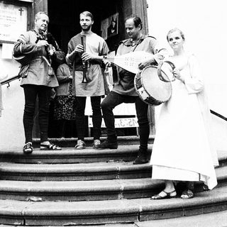 Group performing traditional music outside church entrance.