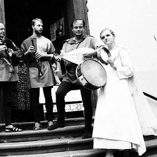 Medieval-themed musicians performing outdoors near entrance.
