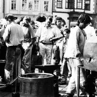 People gathered around blacksmithing demonstration outdoors.