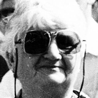 Group of elderly people at outdoor event, holding cameras.