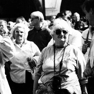 Group of elderly people at outdoor event, holding cameras.