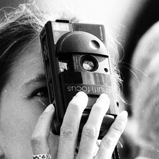 Woman taking photo with vintage camera near Prague guidebook.
