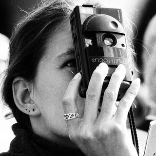 Woman taking photo with vintage camera near Prague guidebook.