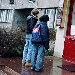 Chinese restaurant with yellow awning, red door, people walking by in rainy weather.