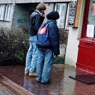 Chinese restaurant with yellow awning, red door, people walking by in rainy weather.